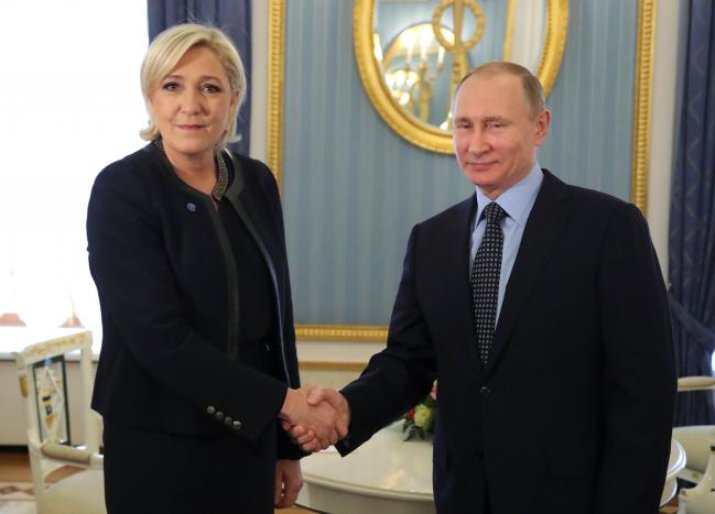 Russian President Putin shakes hands with French far-right party leader Le Pen during their meeting in Moscow